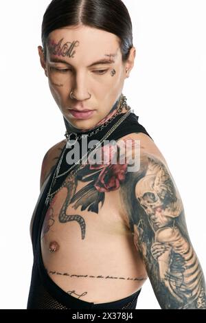 Ein junger, stilvoller Mann, der stolz ein Skelett-Tattoo in einem Studio vor grauem Hintergrund zeigt. Stockfoto