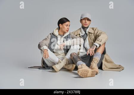 Ein Mann und eine Frau, die auf dem Boden saßen, vertraten tiefe Diskussionen. Die Frau in einem stilvollen Trenchcoat sieht aufmerksam aus. Stockfoto
