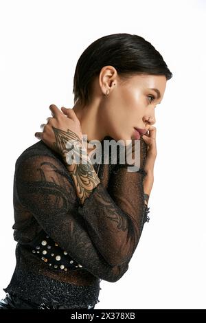 Eine junge Frau mit einem auffälligen Tattoo am Arm, die mit ihrem Partner in einem Studio vor grauem Hintergrund steht. Stockfoto