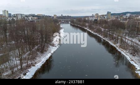 Drohnenfotografie von der winterlichen Stadtlandschaft und dem Fluss, der durch sie fließt, während des sonnigen Wintertages Stockfoto