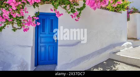 Europa Griechenland Santorini Reiseurlaub. Blick auf die malerische Aussicht auf das berühmte Reiseziel. Romantische blaue Tür mit rosa Blumen, idyllische Natur Stockfoto