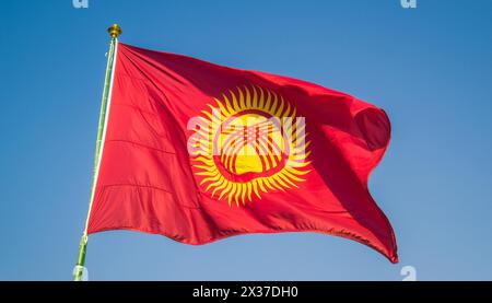 Die Fahne von Kirgisistan, Kirgisien, flattert im Wind, isoliert gegen blauer Himmel Stockfoto