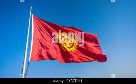 Die Fahne von Kirgisistan, Kirgisien, flattert im Wind, isoliert gegen blauer Himmel Stockfoto