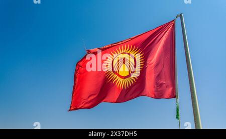 Die Fahne von Kirgisistan, Kirgisien, flattert im Wind, isoliert gegen blauer Himmel Stockfoto