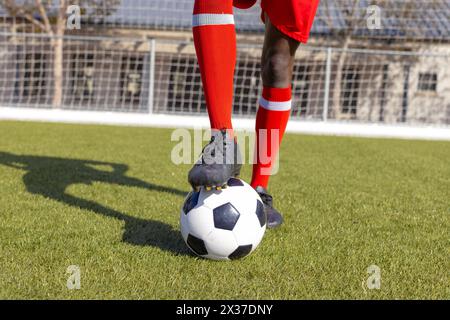 Afroamerikanische Jugend in roten Socken, tritt draußen beim Fußball auf Stockfoto