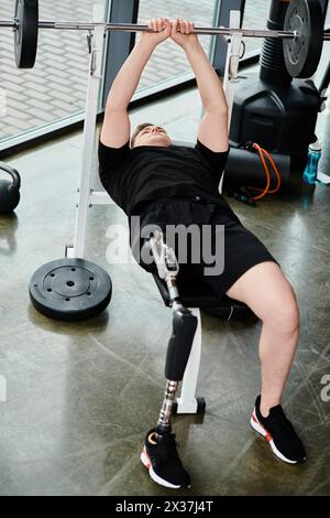 Ein behinderter Mann mit einer Beinprothese, der ein schwarzes Hemd trägt, führt eine Langhantelhocke in einem Fitnessstudio aus. Stockfoto