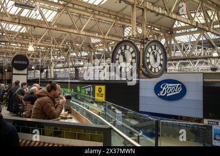 Zugpassagiere essen in einem schnellen Fiood Restaurant neben der berühmten Uhr in Waterloo Station, Lonodn, Großbritannien Stockfoto