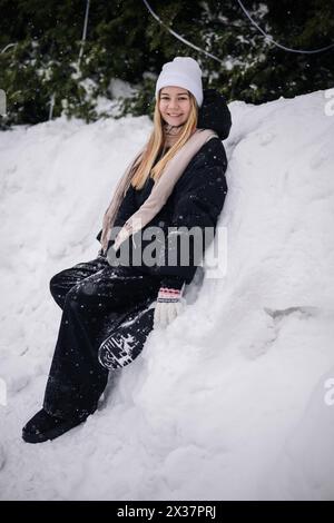 Porträt eines Teenagers, der im Winter in einer Schneelage sitzt. Stockfoto