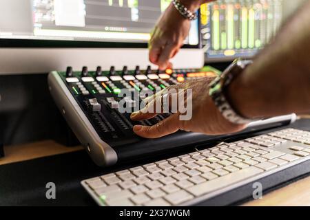 Nahaufnahme der Tontechniker-Hände, die die Bedienelemente an einer Tonmischkonsole anpassen – Präzision und Erfahrung in der Aufnahme und Produktion von Musik-Audio. Stockfoto