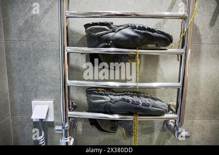 Wanderschuhe trocknen nach dem großen Camping. Schwarze Stiefel zum Wandern, liegen auf dem Trockner im Badezimmer. Stockfoto