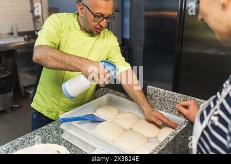 Der Koch Pizzamacher überprüft, ob der Teig fertig ist, die Teigkugeln. Hochwertige Fotos Stockfoto