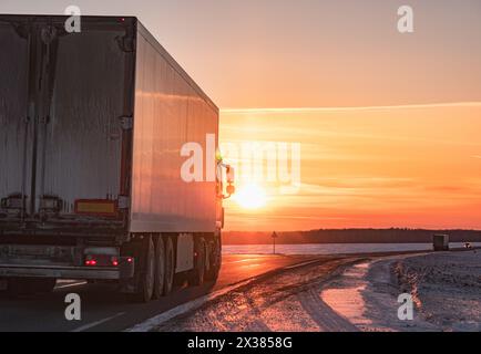 Semi-Truck fährt auf einer verschneiten Autobahn bei Sonnenuntergang im Winter Stockfoto
