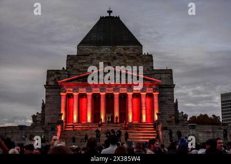 Der Schrein der Erinnerung wird während des ANZAC Day Dawn Service am Melbourne Shrine of Remembrance Memorial rot beleuchtet. Der Dawn Service wird als Teil der ANZAC Day Zeremonien durchgeführt, um diejenigen zu ehren, die in der Schlacht gefallen sind. Während des Ersten Weltkriegs wurde die Dämmerung zu einer bevorzugten Zeit für Angriffe. Soldaten in Verteidigungspositionen wurden vor Sonnenaufgang im Dunkeln geweckt und bemannten ihre Waffen vor dem ersten Licht. Nach dem Ersten Weltkrieg suchten zurückgekehrte Soldaten die Kameradschaft, die sie in den ruhigen, friedlichen Momenten vor Sonnenaufgang fühlten. In Erinnerung an die Momente der Morgenröte vor der Schlacht wurde ein Gedenkgottesdienst zum impo Stockfoto