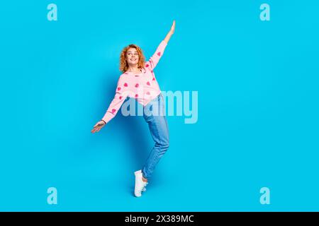 Foto in voller Länge von attraktiven jungen Frau Zehenspitzen tanzen Blick leerer Raum gekleidet stilvolle rosa Kleidung isoliert auf blauem Hintergrund Stockfoto