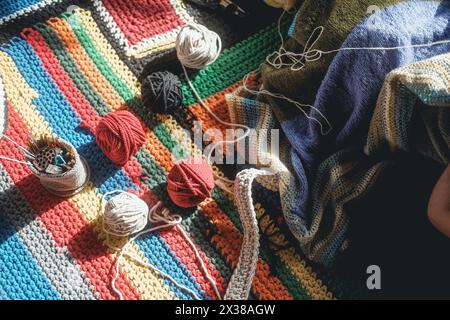 Draufsicht auf eine bunte Strickdecke mit Kugeln aus mehrfarbigen Wollfäden Stockfoto