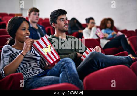 Filme, Verabredungen und Pärchen in Kinos bei Nacht mit Popcorn zum Entspannen und im Theater mit Freude. Film, Erfahrung und Leute im Publikum genießen Spaß Stockfoto