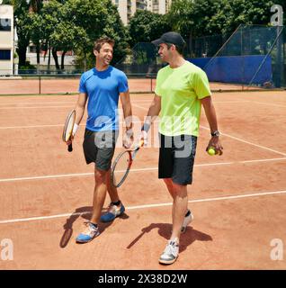 Sport, Tennis und Männer mit Spiel, Training und Teamwork für Wettkämpfe, Schläger und Konversation. Menschen, Spieler und Freunde mit Sonnenschein, Fitness Stockfoto