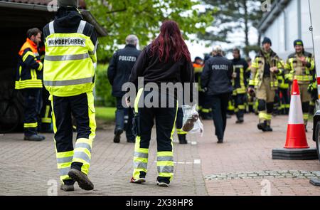 Elm, Deutschland. April 2024. Ein Hundeführer hält eine Tasche mit Kinderschuhen. Freiwillige Feuerwehrleute stehen nach ihrer Mission vor der Essenstheke. Der sechsjährige Arian aus Elm (Bezirk Bremervörde) bleibt am vierten Tag in Folge vermisst. Quelle: Philipp Schulze/dpa/Alamy Live News Stockfoto