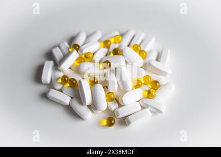 Ein Haufen weißer und gelber Pillen und Kapseln auf weiß Stockfoto