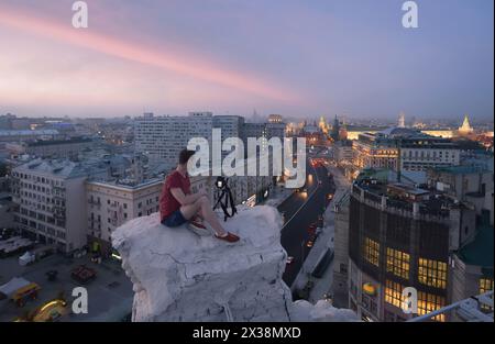 Der Mann sitzt mit der Kamera auf dem Dach und schießt morgens auf die Twerskaja-Straße in Moskau Stockfoto