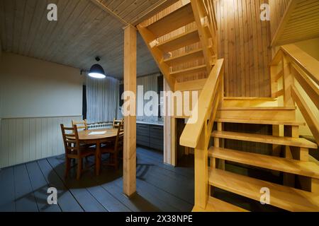 Innenraum des Holzhauses, Küche mit Tisch und Stühlen, Treppe zum zweiten Stock. Stockfoto