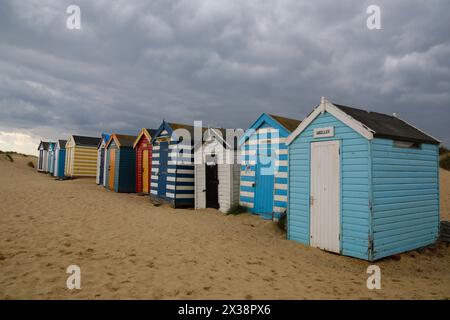 Southwold, Suffolk, Großbritannien. April 2024. Wetter in Großbritannien: Mischung aus Sonnenschein und Schauern in Southwold, Suffolk. Alte Strandhütten, benannt nach berühmten Menschen und Monarchen, von Sanddünen am Southwold Denes Beach. Quelle: Carolyn Jenkins /Alamy Live News Stockfoto