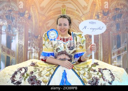 MOSKAU - 4. Dezember 2016: Glückliche Frau (mit Modellveröffentlichung) posiert in Kleid mit Cerealien-Dekoration auf der Ausstellung Foodshow in Sokolniki, Text - ich bin Königin, Stockfoto