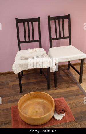 Zwei Stühle mit Handtüchern und Holzschale zum Waschen der Füße im Zimmer Stockfoto