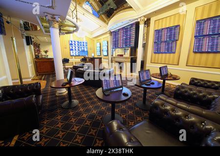 Tische mit Spielcomputern und vielen Bildschirmen im Buchmacherbüro des Casinos, mein Foto auf Bildschirmen Stockfoto