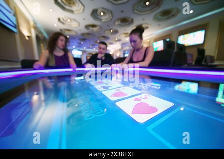 Elektronischer Pokertisch in einem modernen Casino und drei Spieler außer Fokus Stockfoto