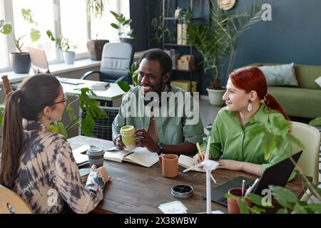 Vielfältiges kreatives Business-Team, das die Arbeit am Meeting-Tisch in einem umweltfreundlichen Büro mit Pflanzen genießt Stockfoto