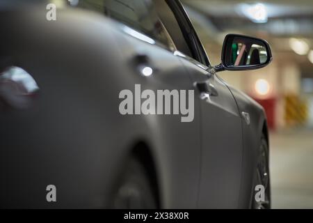 Rechte Seite des modernen Autos in der Tiefgarage, Blick auf den Rückspiegel. Stockfoto