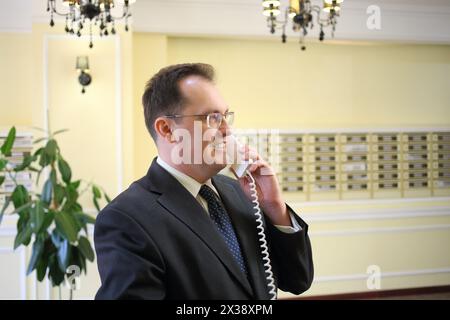 Mann in einem Geschäftsanzug, der am Telefon im Flur des Luxus-Apartmentgebäudes spricht Stockfoto