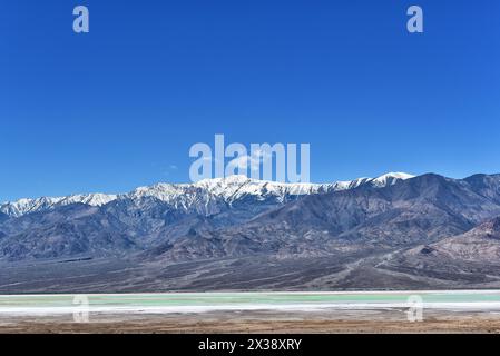 Das grüne Wasser des Sees am Devils Golf Course mit den schneebedeckten Black Mountains im Hintergrund, Death Valley National Park. Stockfoto