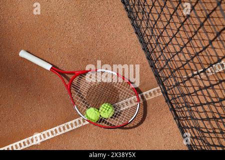 Tennisschläger und zwei Bälle in der Nähe des Netzes auf dem Platz an sonnigen Sommertagen Stockfoto
