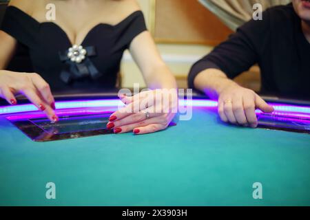 Elektronischer grüner Tisch im modernen Kasino und Hände von zwei Spielern Stockfoto