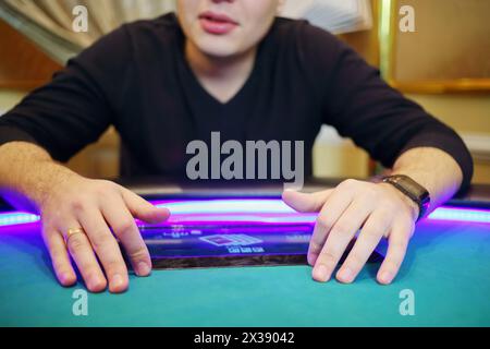 Elektronischer Pokertisch im modernen Kasino und Hände des spielenden Mannes Stockfoto