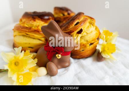 Hausgemachtes traditionelles Ostergebäck liegt auf einer grünen Serviette zusammen mit Narzissen, Kaninchen und Schokoladeneiern. Osterbacken und Dekoration Stockfoto