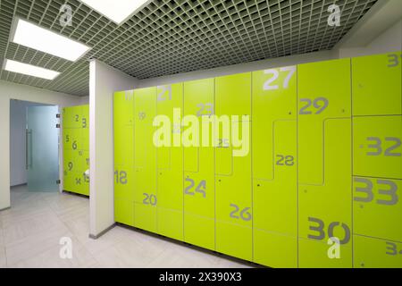 Leere, helle, moderne Garderobe im Fitnessstudio mit vielen grünen Schließfächern Stockfoto