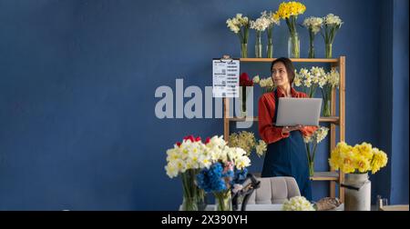 Blumenläuferin, die einen Laptop benutzt, um in ihrem Blumenladen Text zu lesen. Konzept des Kleinbetriebs und der Blumenlieferung. Banner Stockfoto