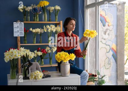 Eine Floristin sammelt einen Strauß gelbe Narzissen und arbeitet in ihrem Blumenladen. März: Konzept Stockfoto