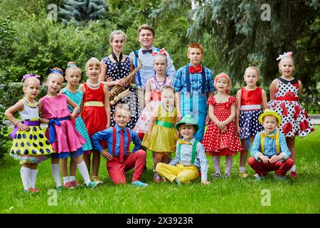 Gruppenporträt von 15 Kindern in hellen Tanzanzügen, die auf dem Rasen posieren. Stockfoto