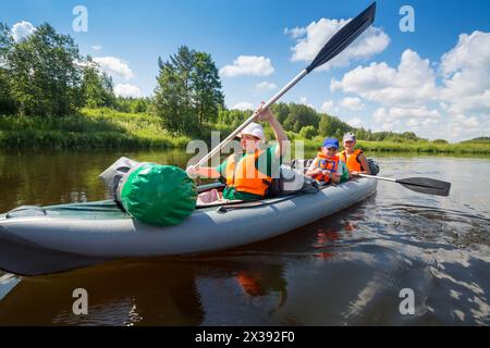 Zwei Frauen mit Rudern und einem kleinen Jungen segeln an sonnigen Sommertagen auf Schlauchbooten auf dem Fluss Stockfoto