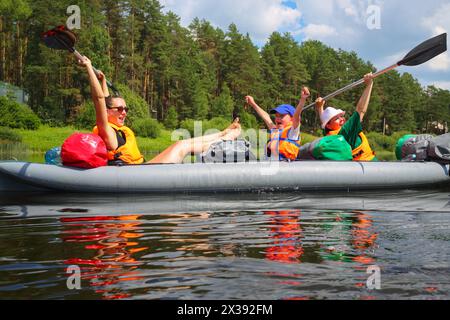 Zwei Frauen und ein kleiner Junge haben Spaß auf einem Schlauchboot auf dem Fluss am sonnigen Sommertag Stockfoto