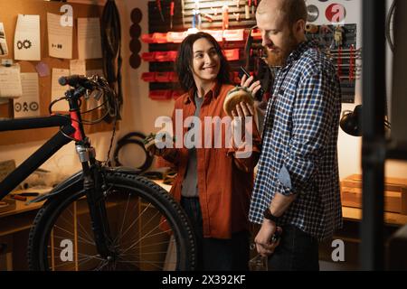 Mann und Frau reparieren modernes Fahrrad in Garage oder Werkstatt, Mittagspause am Arbeitsplatz Stockfoto