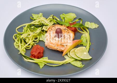 Rotes Fischbrötchen mit geriebenem und in Scheiben geschnittenem Gemüse und Obst auf Teller. Stockfoto