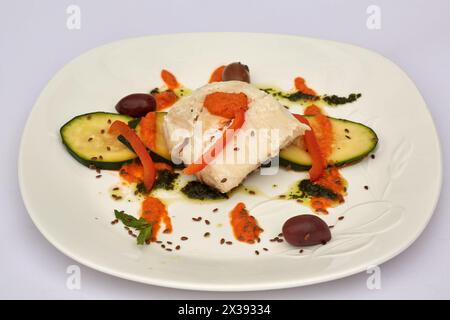 Fisch mit geriebenem und in Scheiben geschnittenem Gemüse und Sauce auf Teller. Stockfoto