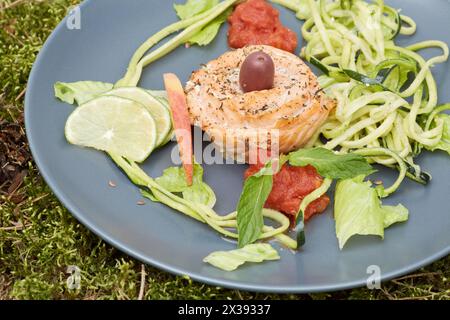 Rotes Fischbrötchen mit geriebenem und in Scheiben geschnittenem Gemüse und Obst auf Teller. Stockfoto