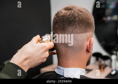 Der Friseur rasiert männliche Okziput mit Trimmer in der Nähe des Friseurs. Professioneller Friseur schneidet Männerhaare mit einer Maschine im Friseursalon Stockfoto