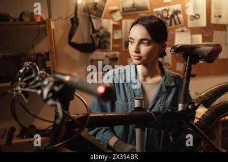 Portraitreparaturfrau in der Fahrradwerkstatt. Fahrradgarage und Startup. Selbstbewusster weiblicher Mechaniker Stockfoto